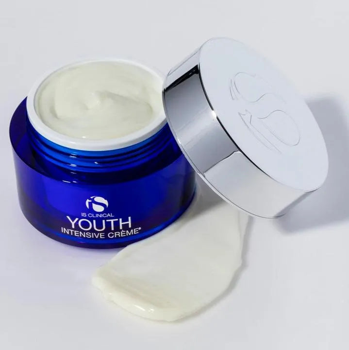 Open blue jar of iS Clinical Youth Intensive Crème with silver lid and a swatch of cream texture