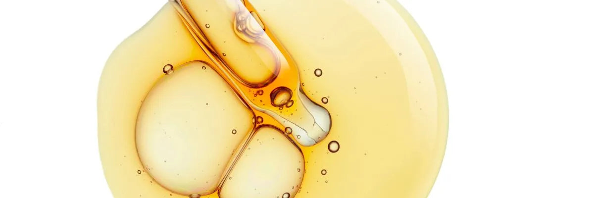 Close-up of amber-coloured retinol serum with visible bubbles and a dropper inside liquid