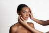 Hands gently examining a woman's facial skin against a clinical-white background
