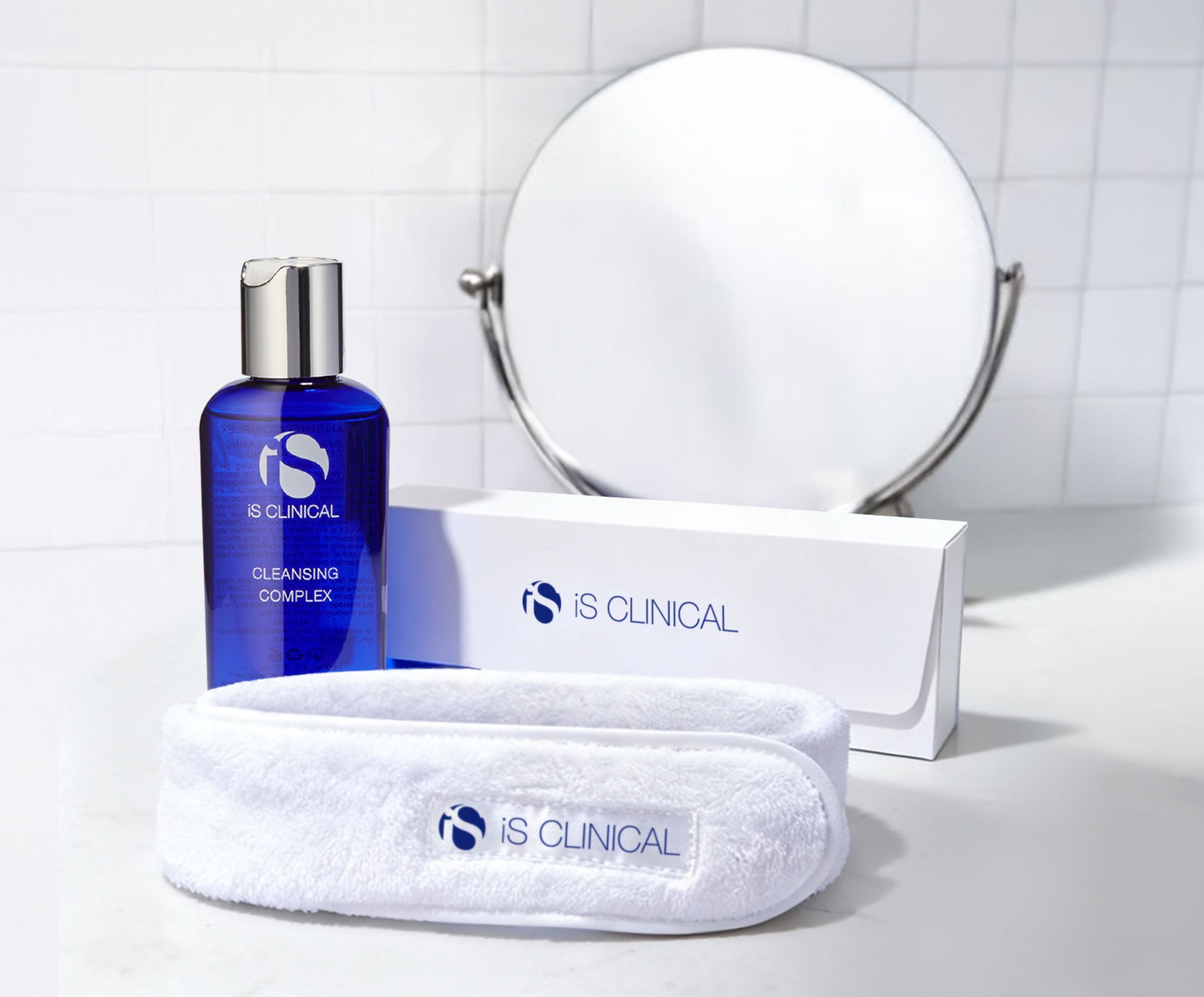 Blue bottle of iS Clinical Cleansing Complex with white branded headband and packaging on white surface
