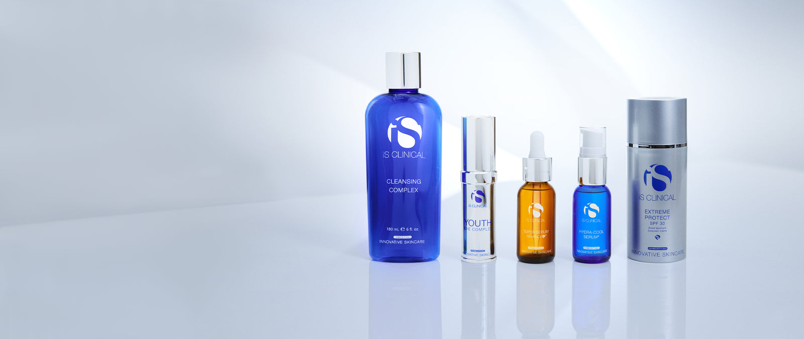 Five iS Clinical skincare products including Cleansing Complex, Youth Eye Complex, Super Serum Advance+, Hydra-Cool Serum, and Extreme Protect SPF 30 on a reflective surface