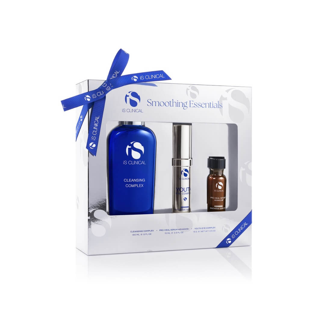 iS Clinical Smoothing Essentials set with blue Cleansing Complex bottle, silver Youth Eye Complex, and brown Pro-Heal Serum Advance+ vial in white box with blue ribbon