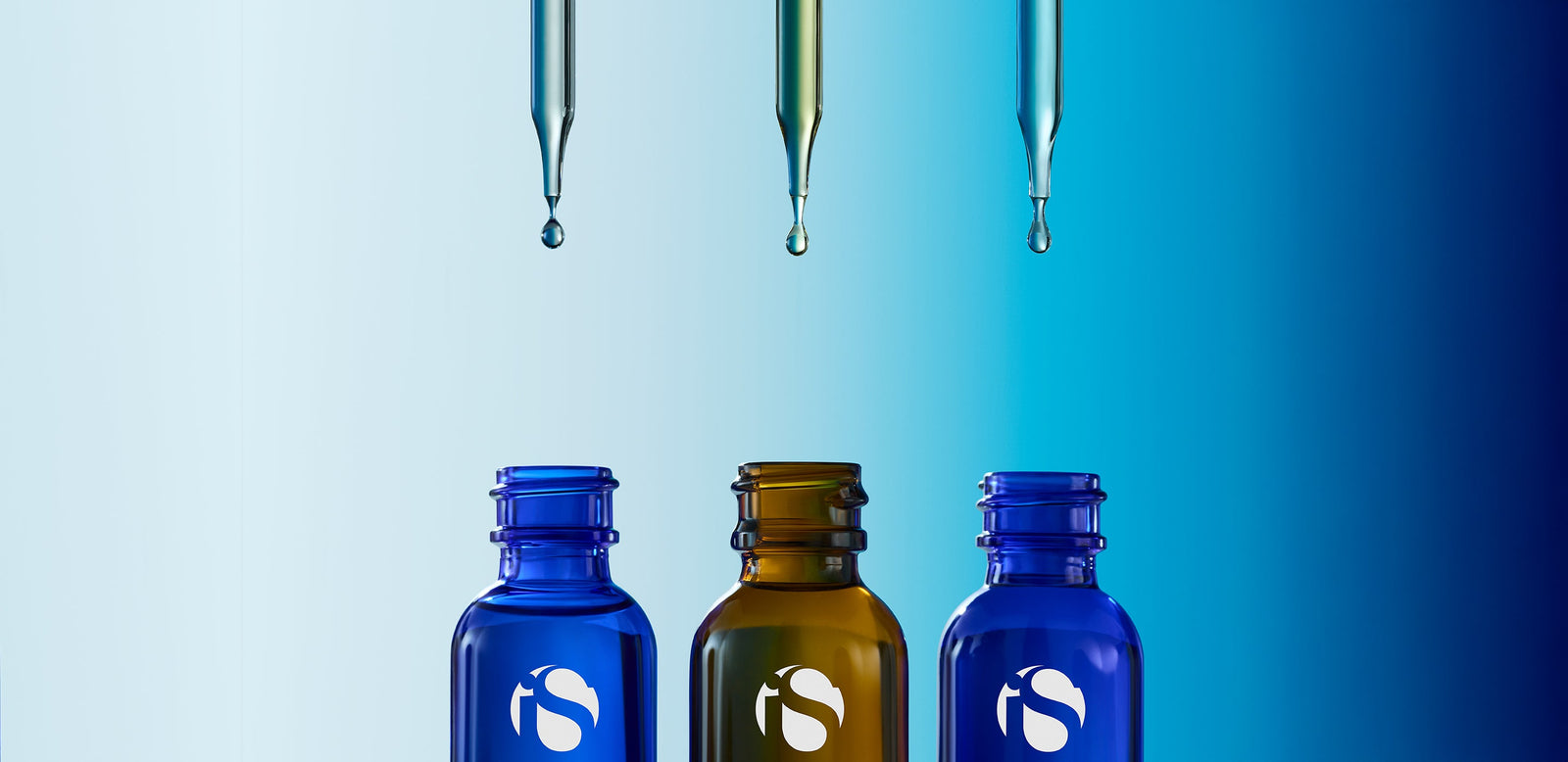 Three open iS Clinical serum bottles in blue and amber glass with droppers releasing liquid drops above