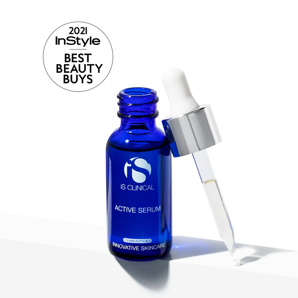 Blue glass bottle of iS Clinical Active Serum with dropper releasing clear liquid on white background