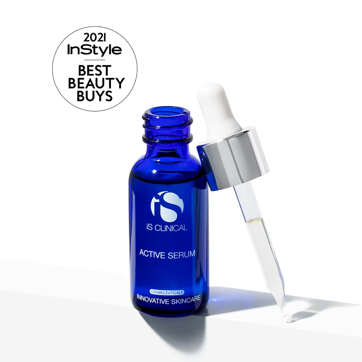 Blue glass bottle of iS Clinical Active Serum with dropper releasing clear liquid on white background