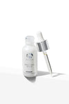 Open frosted glass bottle of iS Clinical Brightening Serum with silver and white dropper beside it on white background