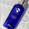 Blue bottle of iS Clinical Cleansing Complex with silver cap on rippled white surface