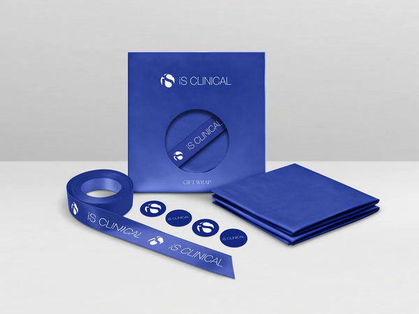 Blue iS Clinical gift wrap pack with ribbon, tissue paper, and branded round stickers on white surface