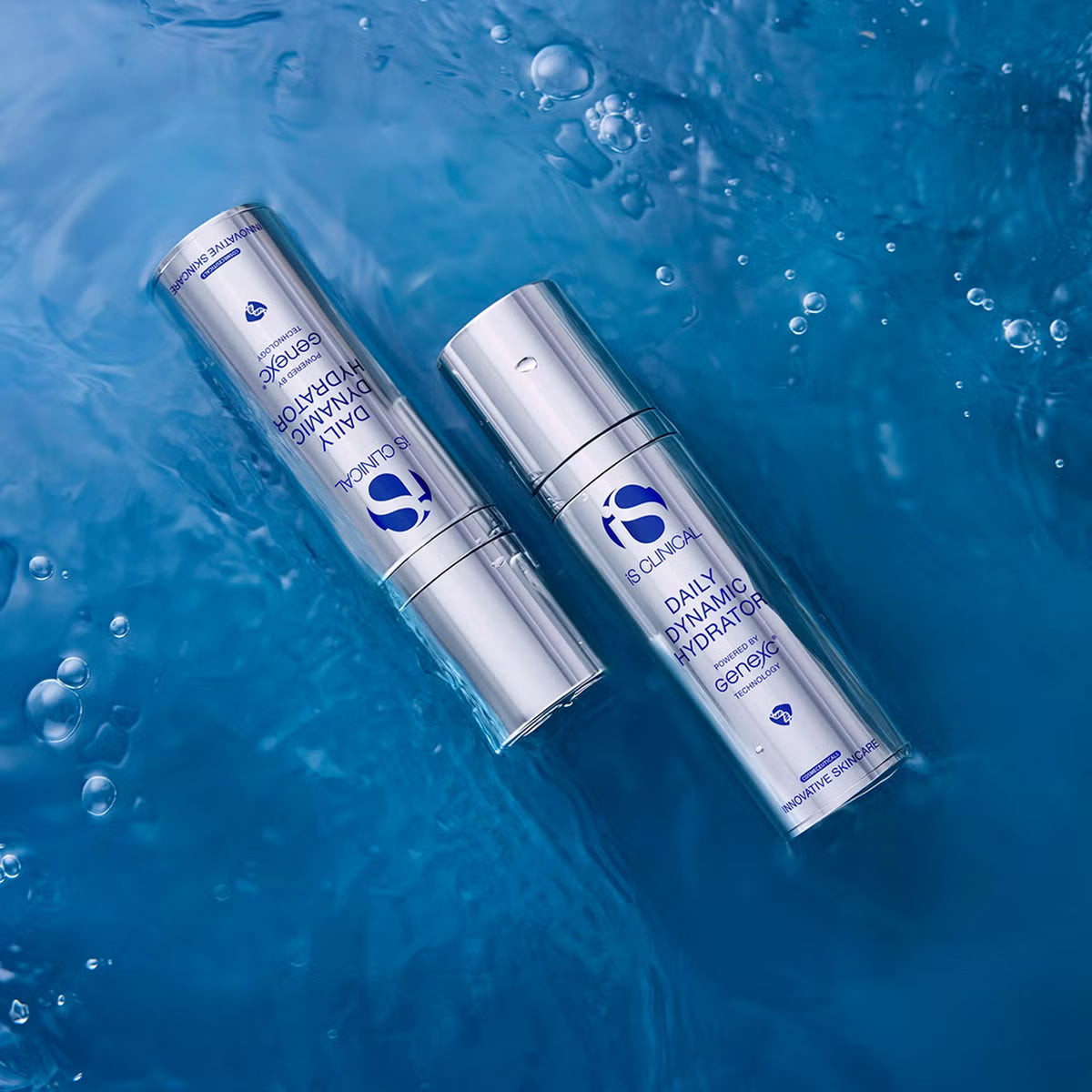 Two silver bottles of iS Clinical Daily Dynamic Hydrator floating on blue water with bubbles