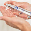 Hand dispensing white cream from silver pump bottle labelled iS Clinical Moisturizing Complex