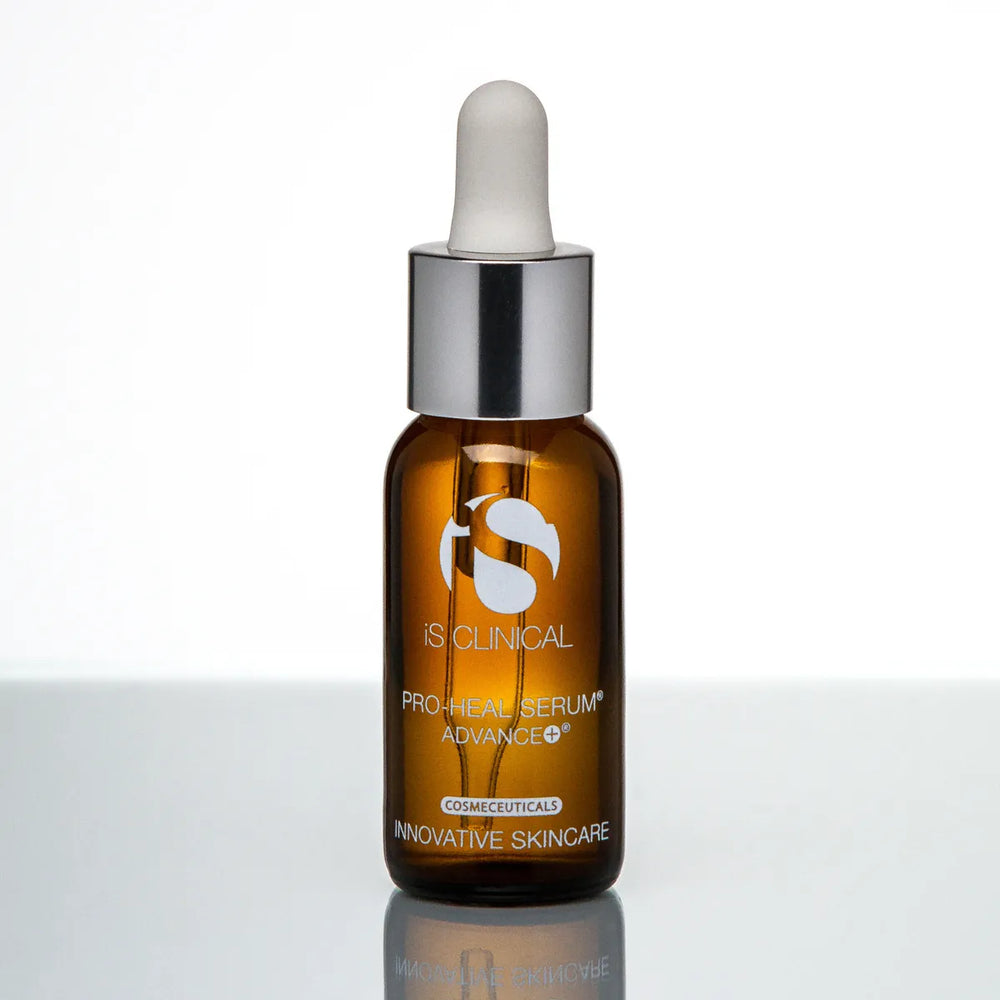 Amber glass dropper bottle of iS Clinical Pro-Heal Serum Advance+ with silver cap on reflective surface