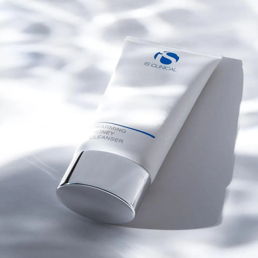 iS Clinical Warming Honey Cleanser tube with silver cap on white surface with soft shadows