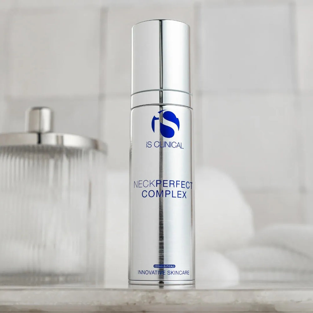 Silver cylindrical bottle of iS Clinical NeckPerfect Complex with blue logo and text on bathroom counter